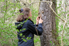 Eine junge Frau modelliert ein Gesicht an einem Baum